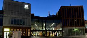 Modern glass and brick building at dusk with a small white electric cargo bike in front