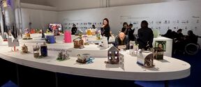 Colourful architectural models on a large white table in an exhibition hall