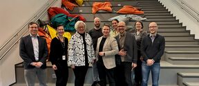 A group of happy people standing in front of a staircase with colorful beanbag chairs.