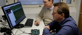 Part of the Xiphera team where they were located at Aalto Startup Center. Two men on the right, sitting, looking at a computer monitor on the left.