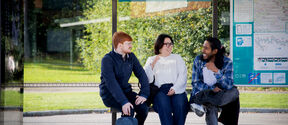 3 people sitting at Aalto University's tram stop