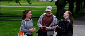 Design students Taija Piikkilä, Kasi Jutila and Leena Hurtig chatting in a green park, holding a friend book.
