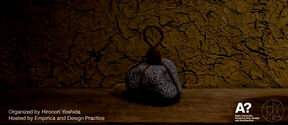 Poster for Kyoto craft workshop; cracked brown wall, grey stone tied with rope on a wooden surface