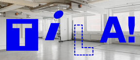 Bright empty industrial room with ducts and large TILA! text in bold blue across the space