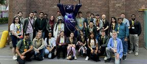 Group of people posing by a purple bear statue at Siemens Energy, against a brick wall