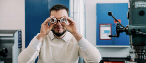 A man peeks through components as if using binoculars.