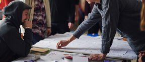 Group of young adults around a table, co-creating with sticky notes in a bright studio
