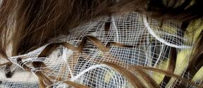 Close-up of a person bending over, brown hair tangled in white netting or fabric