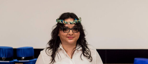 A person in a white dress holding a certificate at a graduation ceremony.