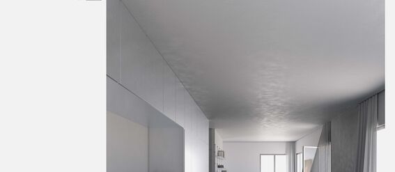 A modern kitchen with grey cabinets and a long island counter. A big window at the end brightens the room.