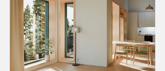 Brightly lit room with large windows, wooden furniture, and a small plant. A dining table with chairs is visible near the kitchen.