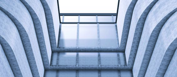 Symmetrical modern building with curved walls and large glass windows forming a central atrium, pale grey tones.