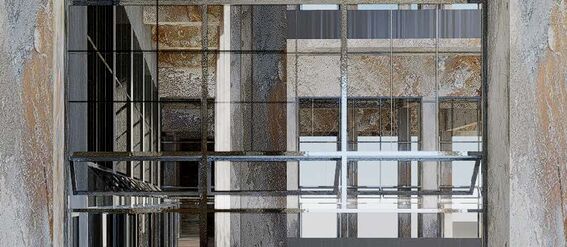 Mirrored space with industrial design elements and multiple reflections of walls and windows.