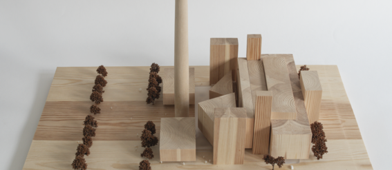 A wooden model of a building with blocks, a tall cylinder, and tiny trees arranged in rows on a light wood base.