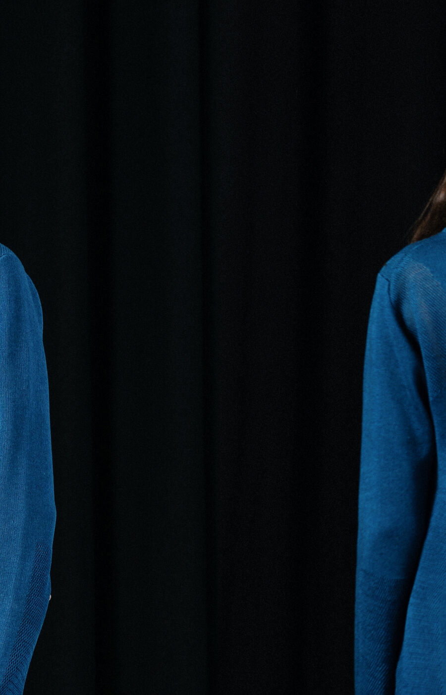 Two views of a person wearing a blue long-sleeved shirt and black trousers against a dark background.