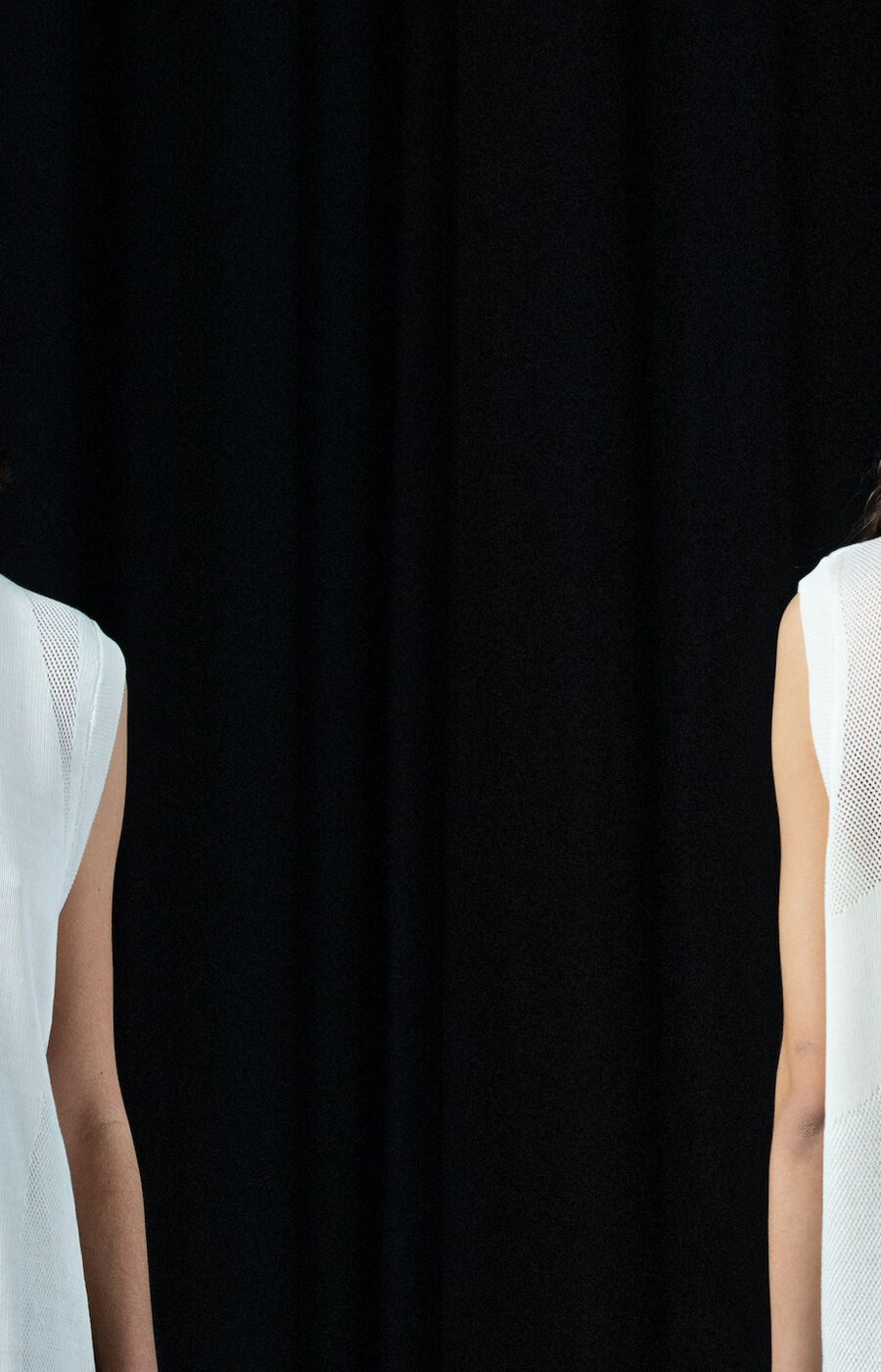 Person wearing a sleeveless white top with mesh details, shown from the front and back against a black background.