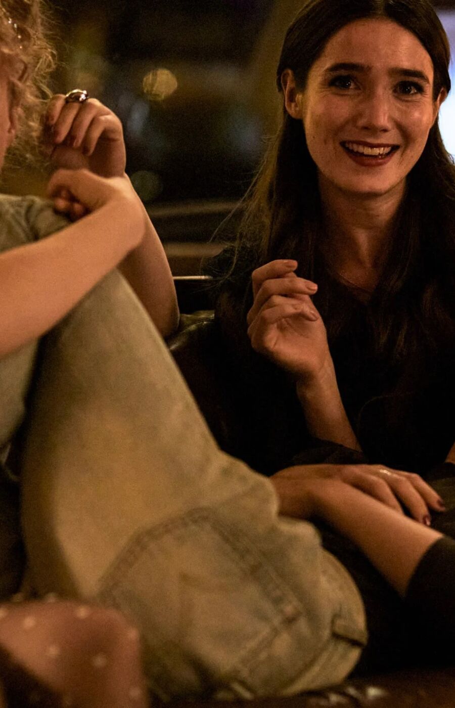 Three people sitting closely together on a sofa in a dimly lit room.