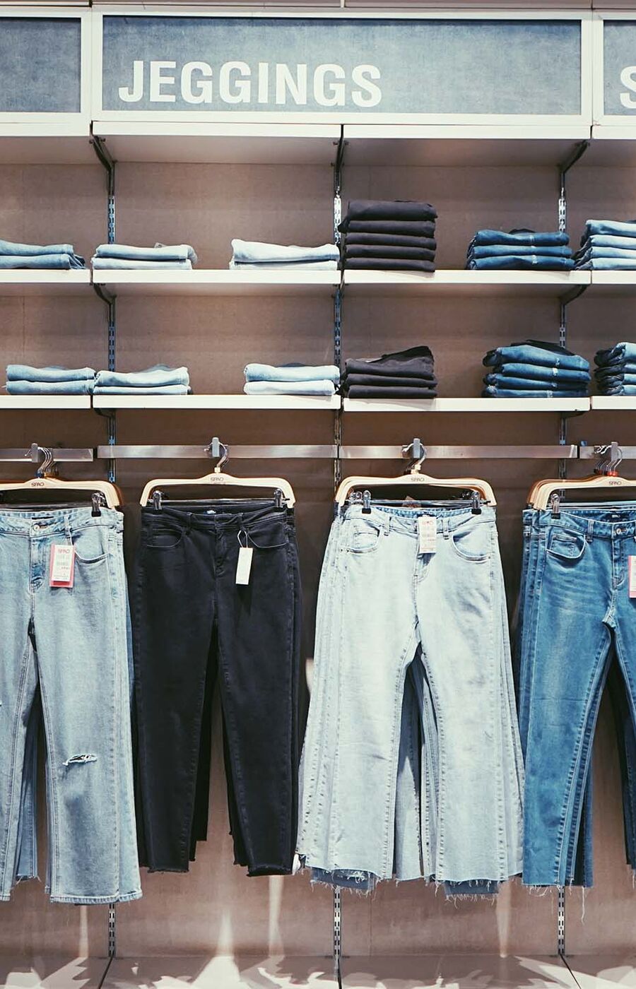 A store display of jeans and jeggings in various styles and colours, labelled 'Skinny' and 'Jeggings'.