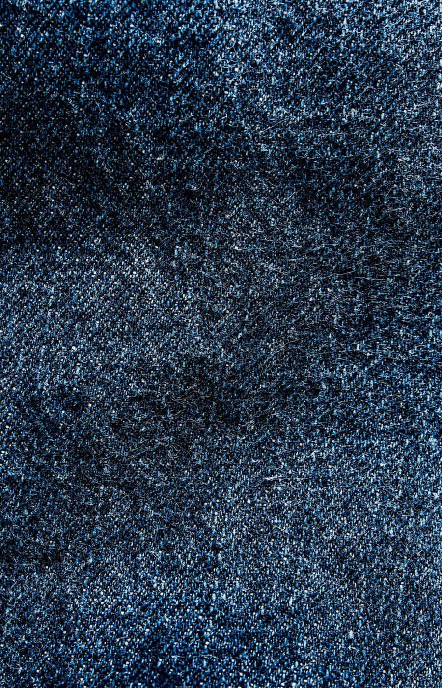 Close-up of dark blue denim fabric with a textured pattern.