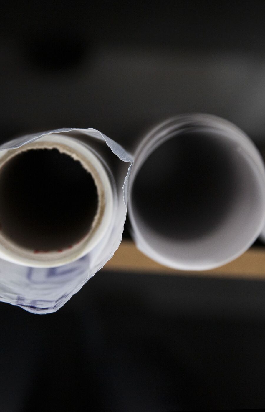 Five rolls of white paper viewed from the top, placed on a wooden surface.