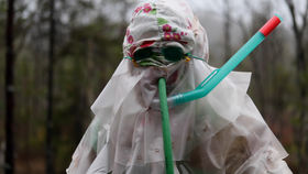 A person in a protective plastic suite in the woods.