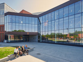 Kauppakorkeakoulu, jonka edustalla istuu neljä opiskelijaa. Kuva: Unto Rautio / Aalto-yliopisto