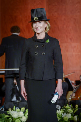 Kuvassa tohtorinhattuun ja mustaan pukuun pukeutunut nainen