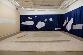 Photo of an art installation consisting of tapestry and fabrics in a gallery space
