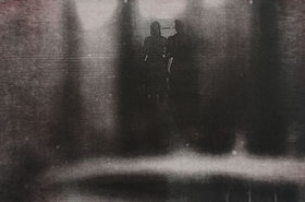 photogravur where there are two persons in the middle with dark surrounding all over