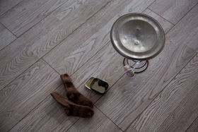 An artwork by Niran Baibulat comprised of felt socks, a sweet tin and a metal cooking place stand on the floor. 