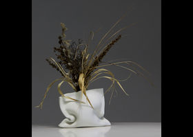 a white ceramic bag-like vase with plants in it