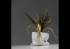 a white ceramic bag-like vase with plants in it