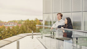 Kaksi opiskelijaa seisomassa Kauppakorkeakoulun kolmannen kerroksen terassilla