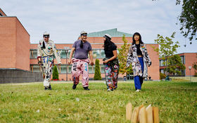 Neljä Aallon opiskelijaa pelaamassa mölkkyä yllään opiskelijahaalarit ja -takit. 