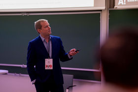 A man holding a clicker on stage and looking away from the camera