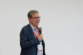 A man with a smug smile is holding a microphone