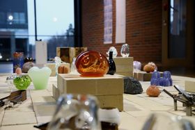 A collection of glass objects exhibited on a layout made of bricks
