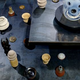 A collection of ceramic objects and a glass sculpture in an exhibition setting