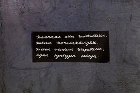 Handwritten text in Finnish on a black paper