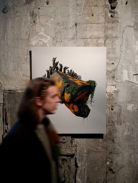 The moss covered rock artwork presented in an exhibition, a blurry person walking by 