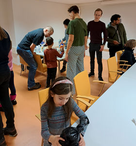 photo showing adults and children sitting and standing around tables
