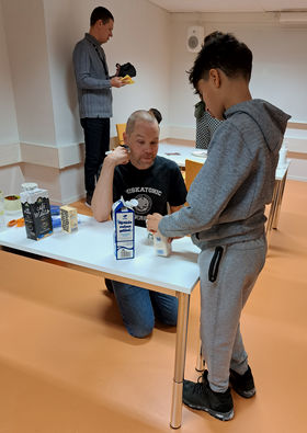 photo showing lecturer Jami Kinnunen kneeling behind a table with a child in the front