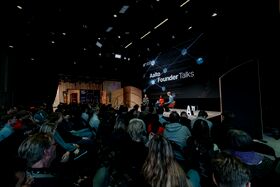 Audience watching three speakers on stage at Aalto Founder Talks event in a large auditorium with a big screen.