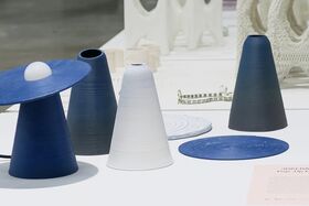 Conical objects in blue, white, and black on a table, including a blue disc with a white sphere on top.