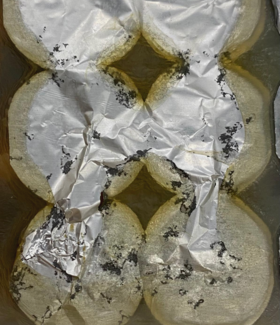 Six circles partially covered with crumpled aluminium foil, with some black spots on the foil.