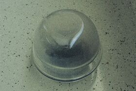 A transparent glass bowl upside down on a speckled countertop.