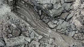 Close-up of grey rocks and soil with visible layers and cracks.