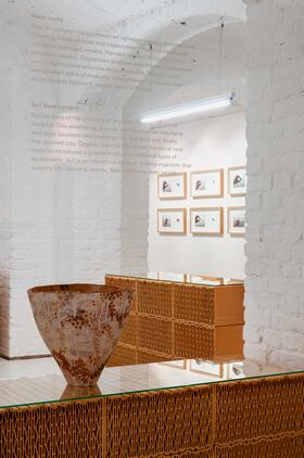 A room with white brick walls, a large ceramic bowl, wicker furniture, and framed pictures on the wall.