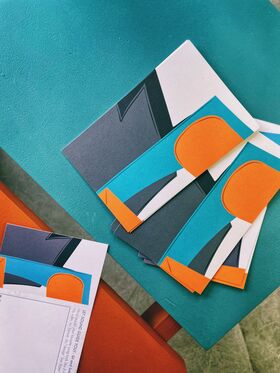 Colourful paper cards with abstract designs on a teal and orange surface.