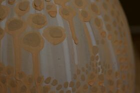 Close-up of a textured surface with beige and light brown circular patterns and streaks.